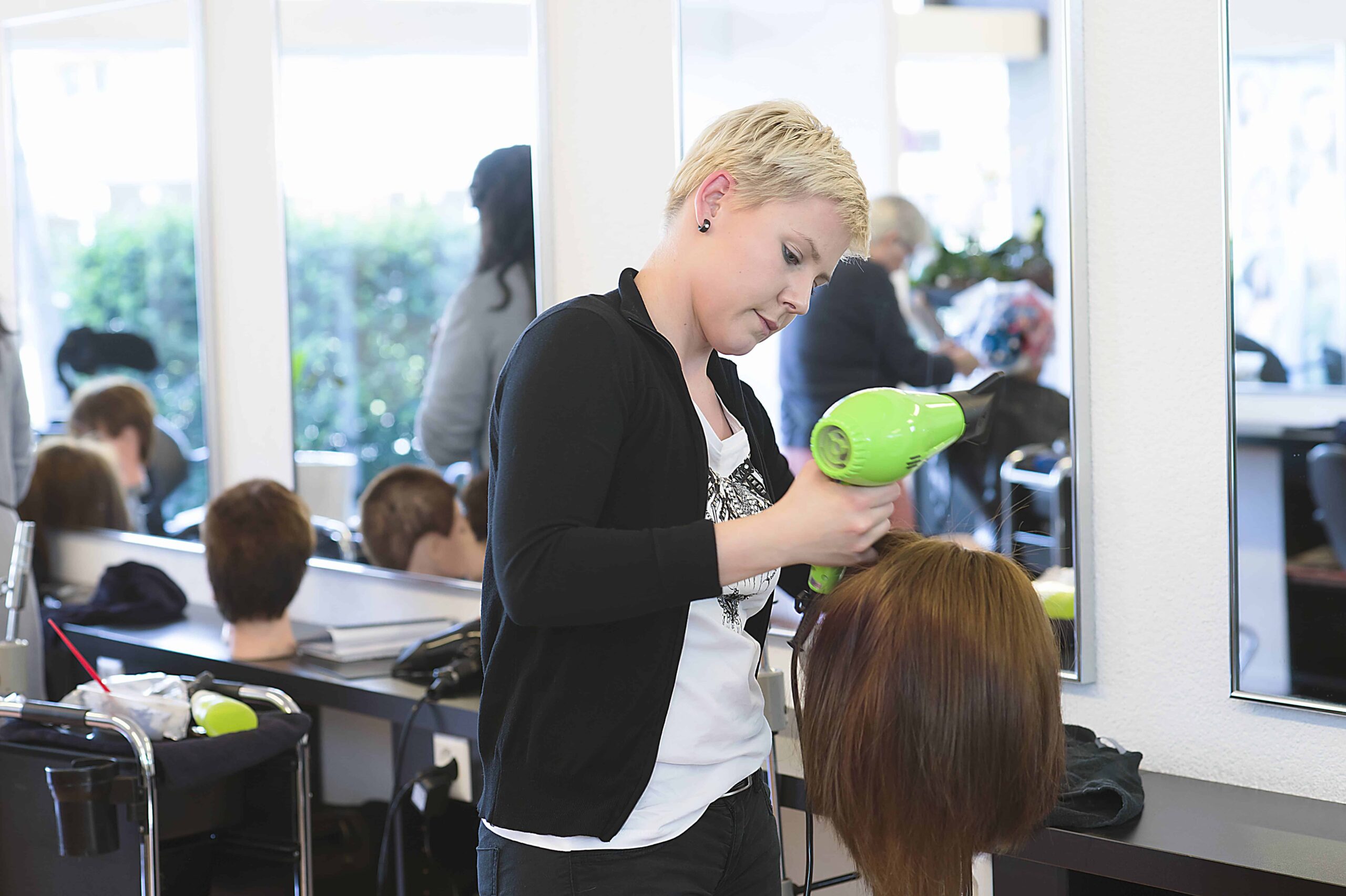 Uma cabeleireira seca o cabelo num sal&atilde;o moderno