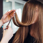 Friseur schneidet langes braunes Haar