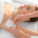 Frau erh&auml;lt professionelle Achselhaarentfernung mit Wachs