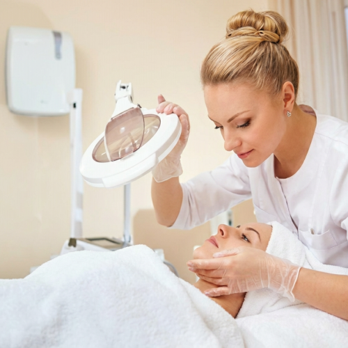 Esth&eacute;ticienne r&eacute;alisant un soin du visage en institut